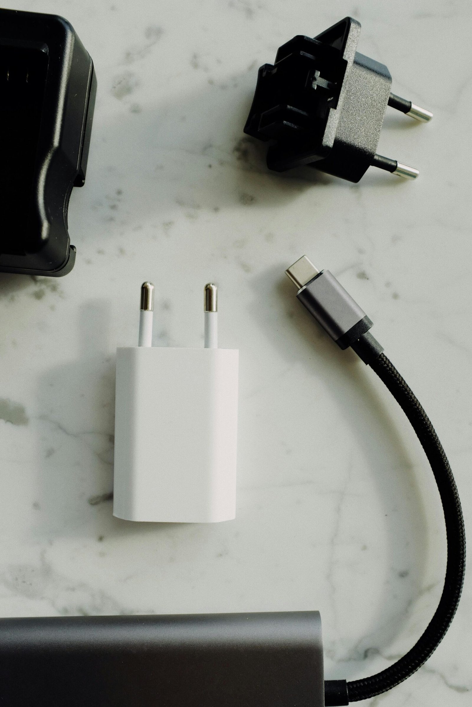 A collection of electrical plugs and a USB-C charger on a marble tabletop. Perfect for tech and electronics themes.